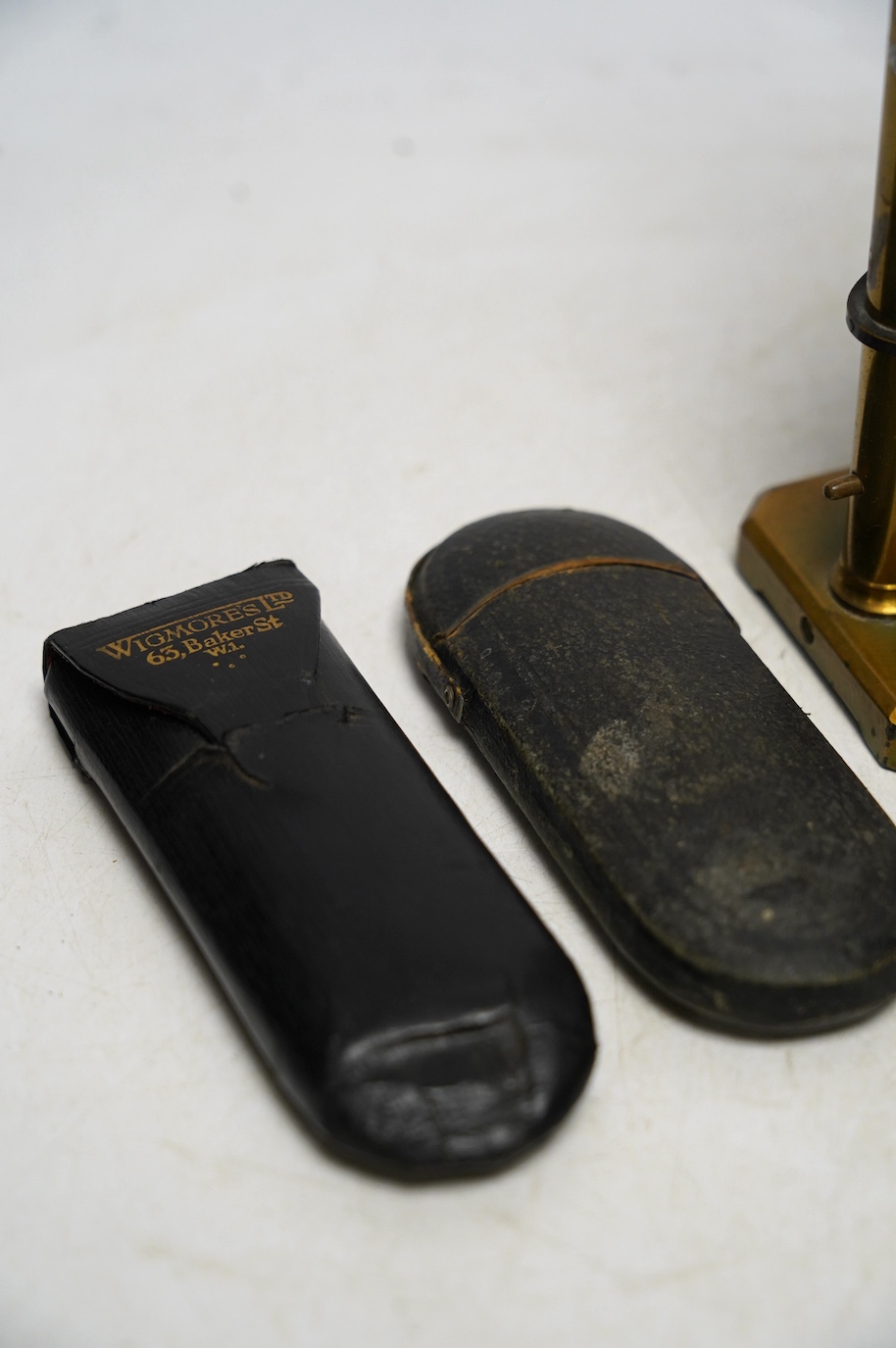 A late 19th century student’s field microscope, 22cm, and three pairs of early 20th century wire framed spectacles in contemporary cases. Condition - fair